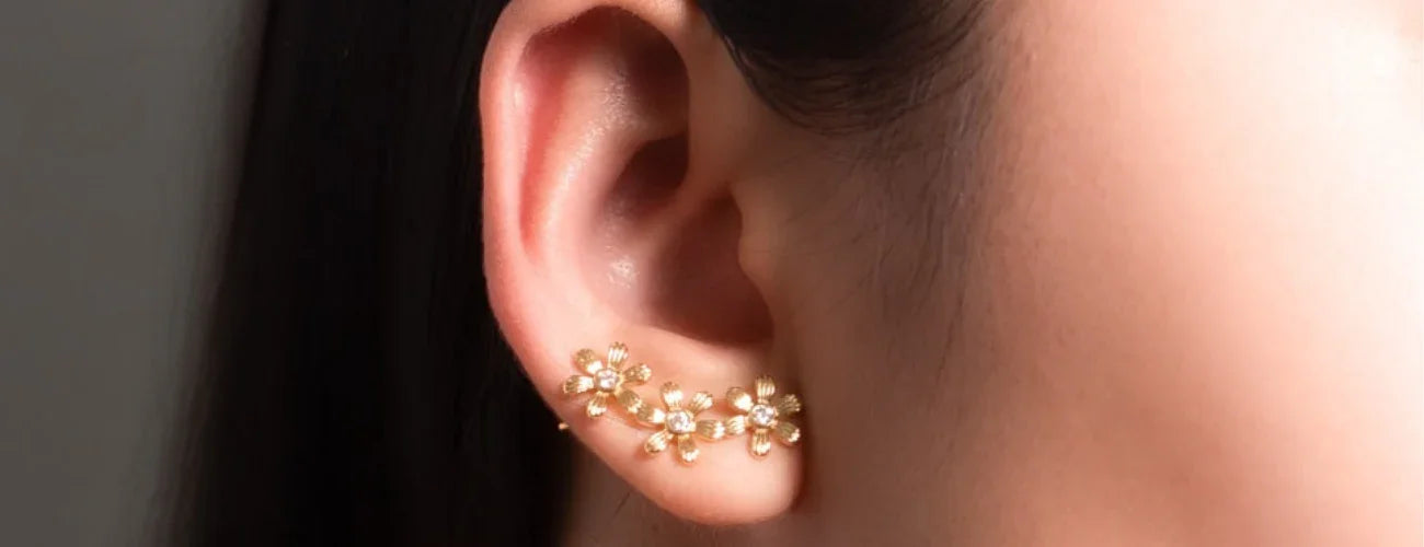 Close-up of gold floral ear climber earring with crystal accents on a woman's ear