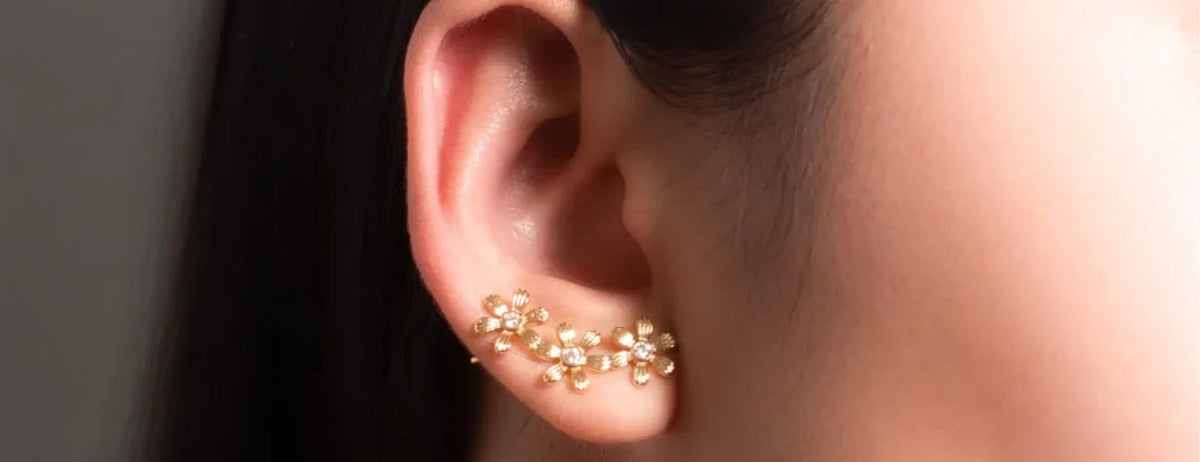 Close-up of gold floral ear climber earring with crystal accents on a woman's ear