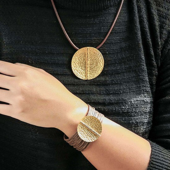 golden coin cord bracelet with large textured gold-tone coin on brown cord worn on wrist and neck