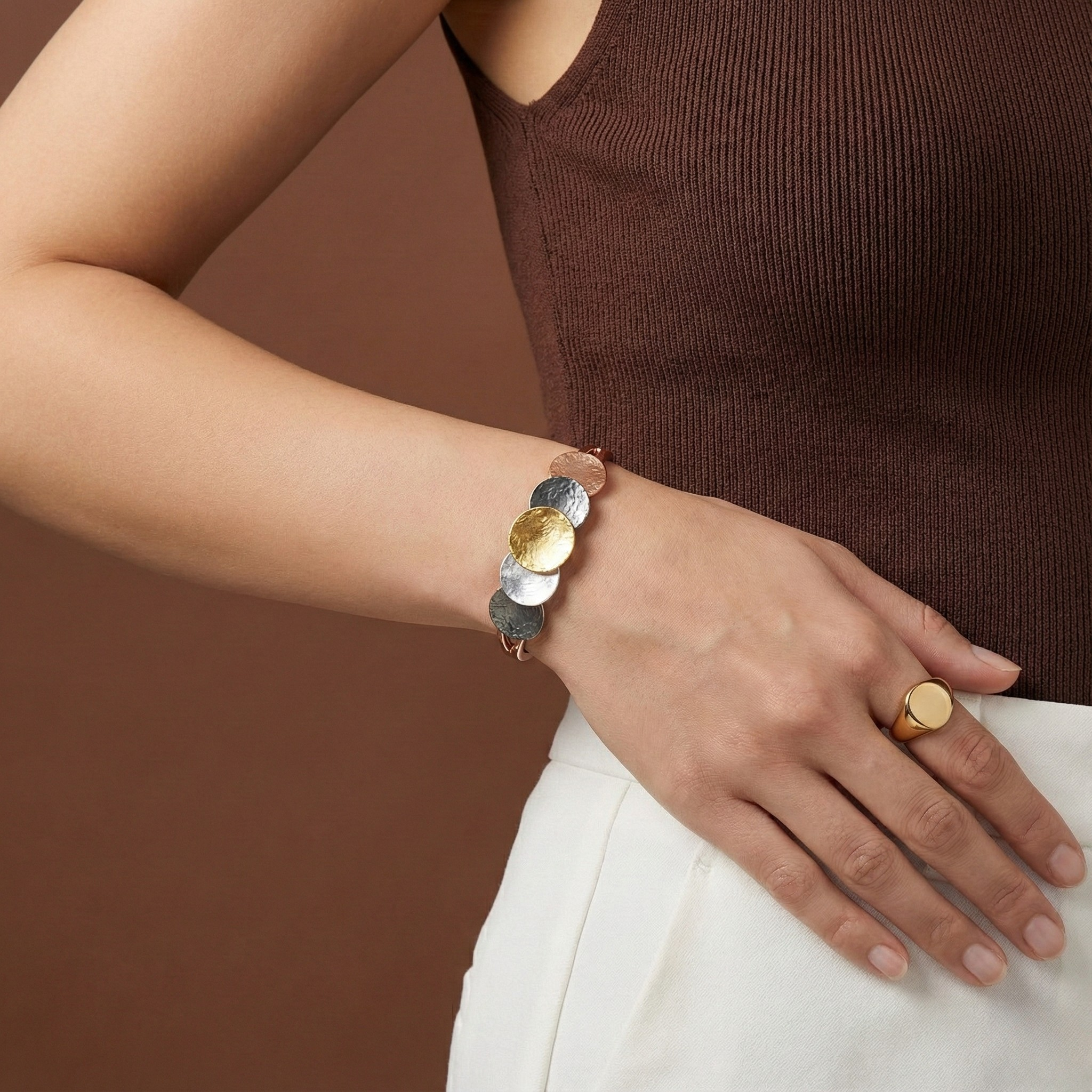 Verona Bracelet with four-tone gold, white, rose gold, and dark grey discs on elastic band worn on wrist
