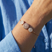 White Sandy Adjustable Bracelet with rose gold finish and dual circle accents on white sand background