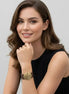 Woman wearing a large gold textured statement bracelet with brown band, minimalist background
